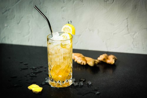 Das Bild zeigt einen gelben Cocktail mit Strohhalm und Zitronendekoration