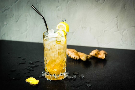 Das Bild zeigt einen gelben Cocktail mit Strohhalm und Zitronendekoration