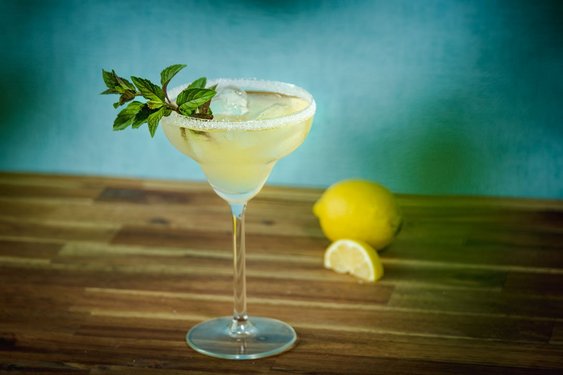 Das Bild zeigt einen Cocktail in einem Martiniglas mit Zuckerrand und Minzdeko
